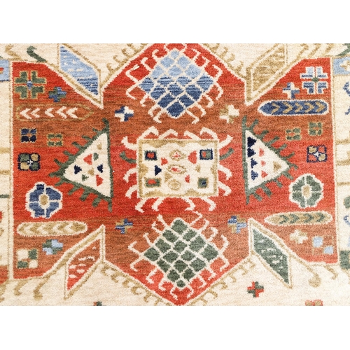 1341 - Carpet / Rug : A cream ground rug with dark salmon / terracotta borders, decorated with geometric an... 