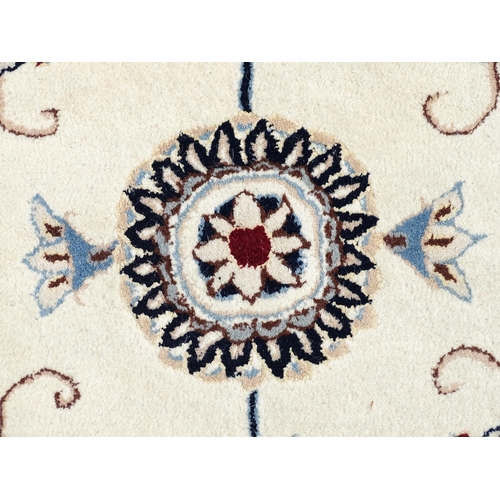 1342 - Carpet / Rug : A beige ground rug with floral and foliate detail worked in shades of blue.  Approx. ... 