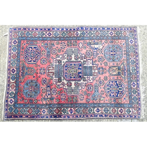 1343 - Carpet / Rug : A salmon pink ground rug with geometric and floral motifs and borders worked in blue ... 