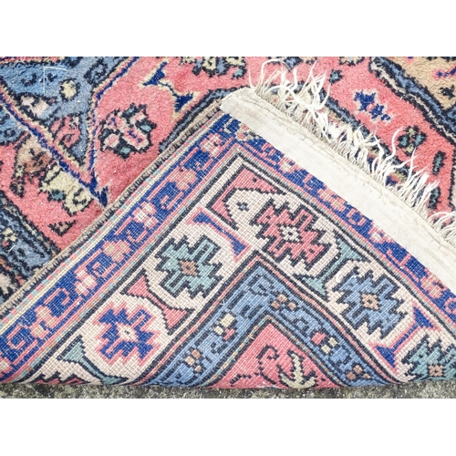 1343 - Carpet / Rug : A salmon pink ground rug with geometric and floral motifs and borders worked in blue ... 