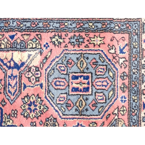 1343 - Carpet / Rug : A salmon pink ground rug with geometric and floral motifs and borders worked in blue ... 