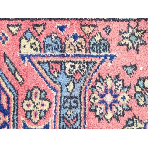 1343 - Carpet / Rug : A salmon pink ground rug with geometric and floral motifs and borders worked in blue ... 