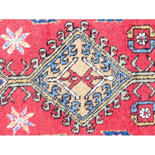 1347 - Carpet / Rug : A red ground runner decorated with central geometric motifs, floral details and geome... 