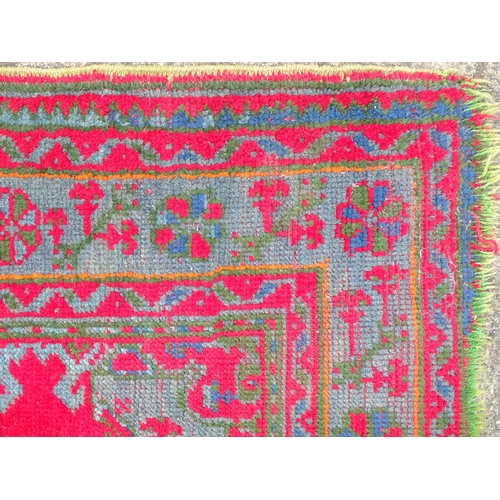 1350 - Carpet / Rug : A  red ground rug decorated with floral, foliate and geometric detail worked in blue ... 