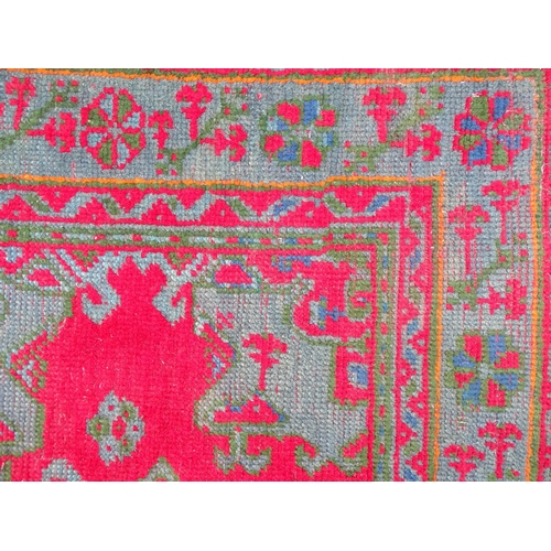 1350 - Carpet / Rug : A  red ground rug decorated with floral, foliate and geometric detail worked in blue ... 