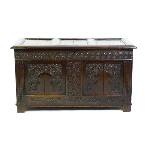 1456 - A late 17thC oak coffer with a three panel lid above a floral wave and scroll carved front, the coff... 