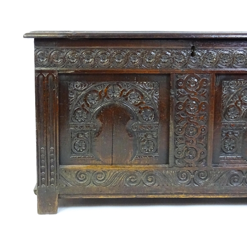 1456 - A late 17thC oak coffer with a three panel lid above a floral wave and scroll carved front, the coff... 