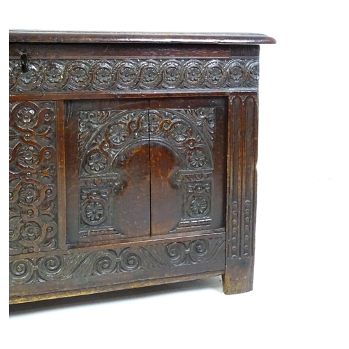 1456 - A late 17thC oak coffer with a three panel lid above a floral wave and scroll carved front, the coff... 