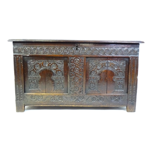 1456 - A late 17thC oak coffer with a three panel lid above a floral wave and scroll carved front, the coff... 