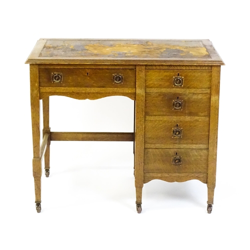 1478 - An Arts & Crafts oak desk, with an inset leather top above a bank of four graduated drawers and one ... 