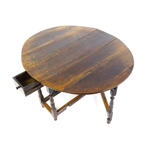 1484 - An early 18thC oak drop flap table, with two demi leaves and a short drawer to one end, the table ra... 