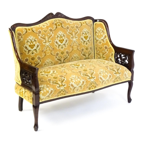 1486 - An early 20thC mahogany settee with a carved and shaped cresting rail above a sprung seat and pierce... 