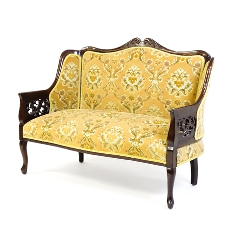 1486 - An early 20thC mahogany settee with a carved and shaped cresting rail above a sprung seat and pierce... 