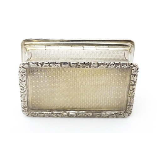 312 - A silver snuff box with waisted sides and engine turned decoration, opening to reveal a gilded inter... 