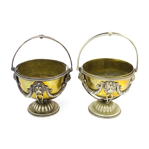 556 - A pair of brass and silver plate pedestal bowls with lions mask and swag detail and swing handles. A... 