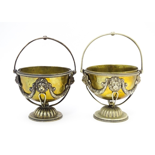 556 - A pair of brass and silver plate pedestal bowls with lions mask and swag detail and swing handles. A... 