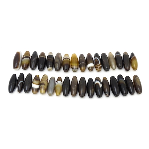 741 - A quantity of Scottish agate loose beads of shaped form, some with banded detail. The largest approx... 