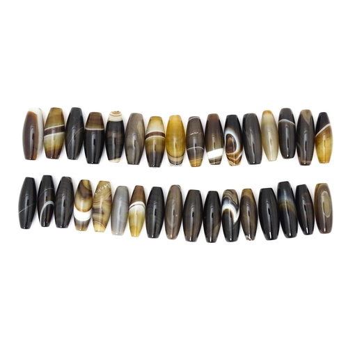 741 - A quantity of Scottish agate loose beads of shaped form, some with banded detail. The largest approx... 