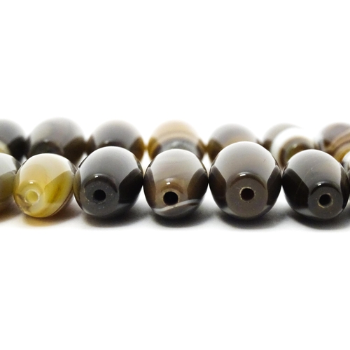 741 - A quantity of Scottish agate loose beads of shaped form, some with banded detail. The largest approx... 