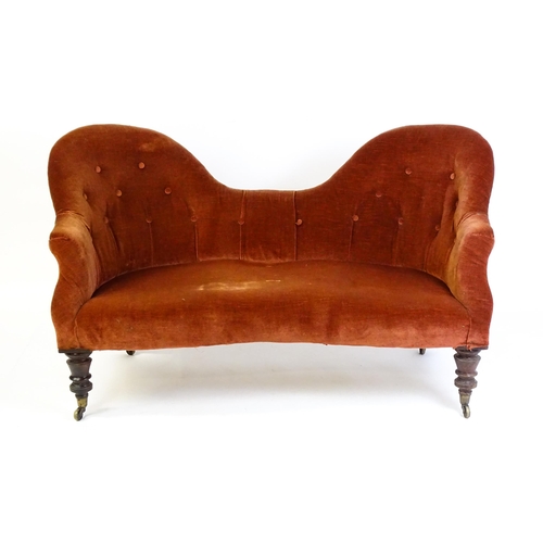 1447 - A late 19thC hump back / camel back sofa with deep buttoned upholstery and sprung seat, the sofa rai... 