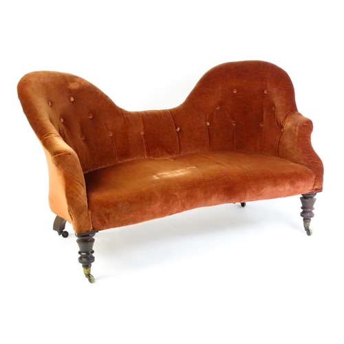 1447 - A late 19thC hump back / camel back sofa with deep buttoned upholstery and sprung seat, the sofa rai... 