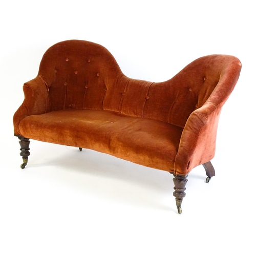 1447 - A late 19thC hump back / camel back sofa with deep buttoned upholstery and sprung seat, the sofa rai... 