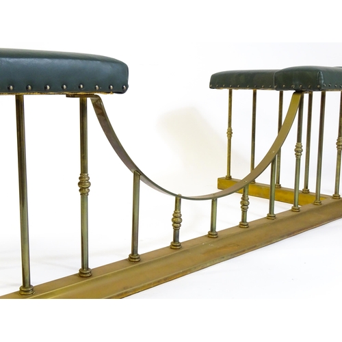 1460 - A late 20thC club fender, with two leather upholstered seats raised on brass railed supports and a s... 