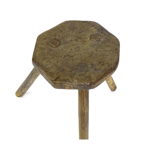 1500 - A 19thC primitive stool of large proportions, the octagonal top raised on three legs. 24