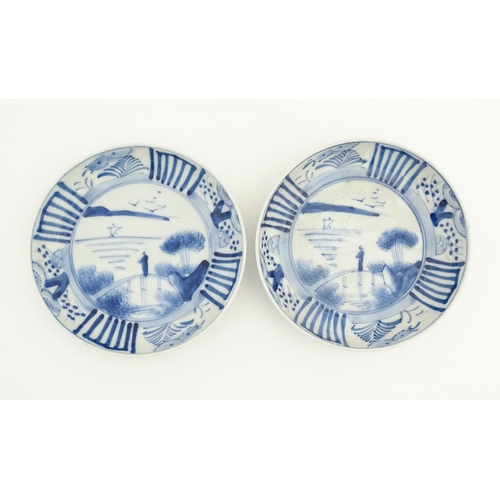 75 - A pair of Oriental blue and white dishes each depicting a figure on a bridge looking out to sea with... 