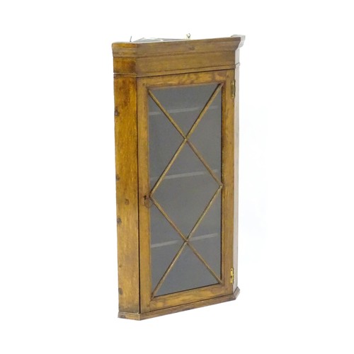 197 - An early 20thC oak corner cupboard with a moulded cornice above an astragal glazed door containing f... 