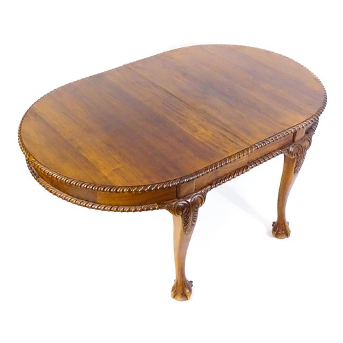 237 - A mahogany dining table with an oval, gadrooned table top above four large cabriole legs with acanth... 