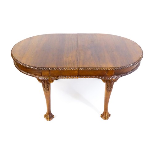 237 - A mahogany dining table with an oval, gadrooned table top above four large cabriole legs with acanth... 