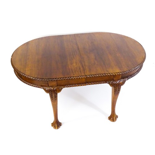 237 - A mahogany dining table with an oval, gadrooned table top above four large cabriole legs with acanth... 