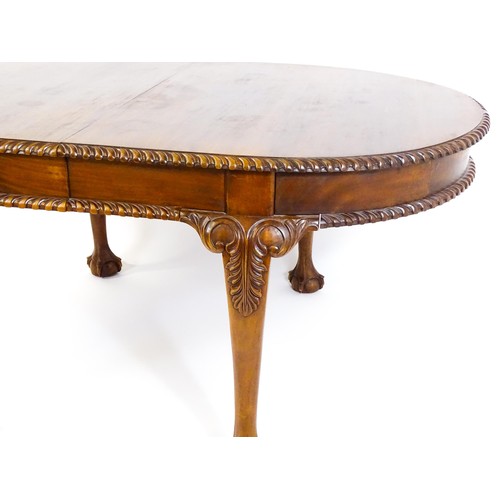 237 - A mahogany dining table with an oval, gadrooned table top above four large cabriole legs with acanth... 