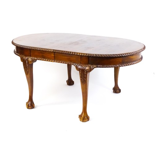 237 - A mahogany dining table with an oval, gadrooned table top above four large cabriole legs with acanth... 