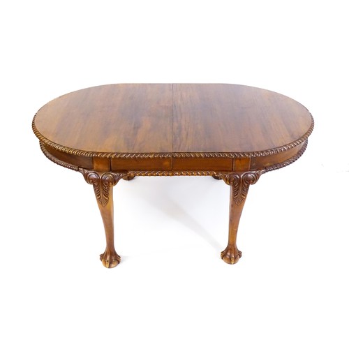 237 - A mahogany dining table with an oval, gadrooned table top above four large cabriole legs with acanth... 