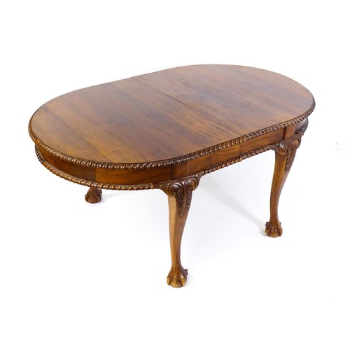 237 - A mahogany dining table with an oval, gadrooned table top above four large cabriole legs with acanth... 