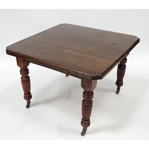 380 - An early 20thC dining table with canted corners and raised on turned tapering legs with reeded decor... 