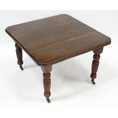 380 - An early 20thC dining table with canted corners and raised on turned tapering legs with reeded decor... 