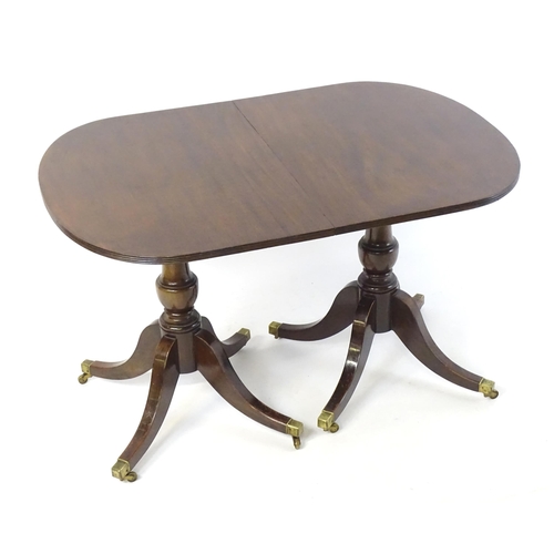 419 - A Regency style double pedestal mahogany dining table with a reeded edge and an additional leaf. Un-... 