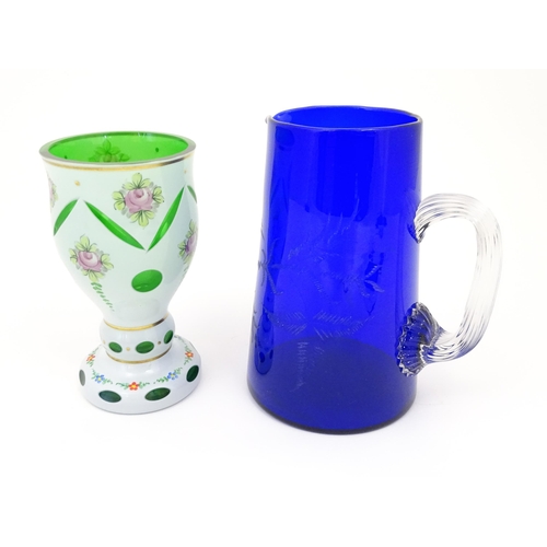 445 - A Bohemian glass goblet with green glass detail and floral decoration together with a blue glass jug... 