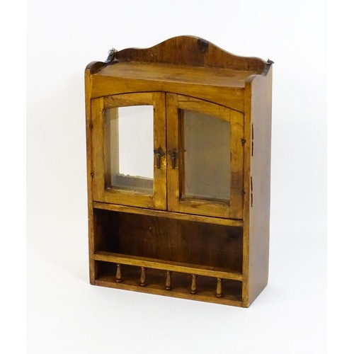 448 - A pine hanging wall cabinet, with two glazed doors above a small rack with a gallery of turned finia... 