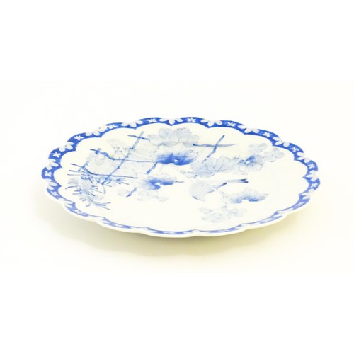 496 - A Japanese blue and white plate with scalloped edge, decorated with a bird perched on a branch with ... 