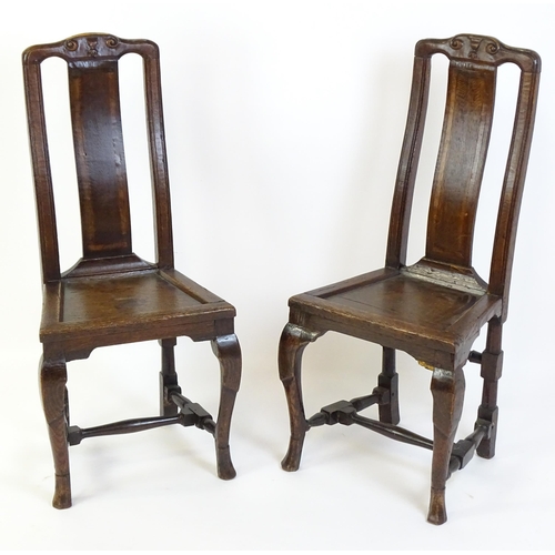 1508A - A pair of early 18thC oak side chairs, with carved top rails decorated with scrolls and floral detai... 