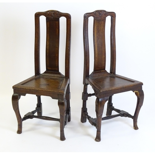 1508A - A pair of early 18thC oak side chairs, with carved top rails decorated with scrolls and floral detai... 