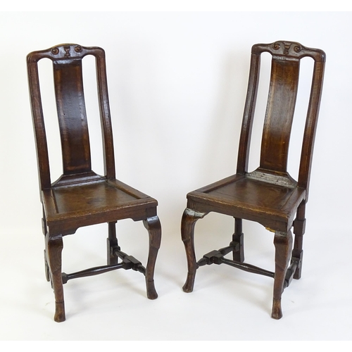 1508A - A pair of early 18thC oak side chairs, with carved top rails decorated with scrolls and floral detai... 