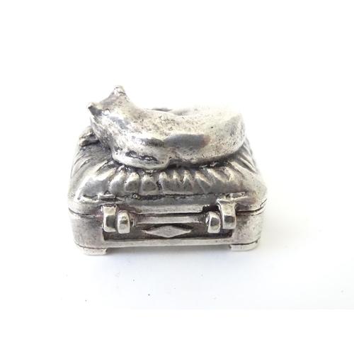 519 - A white metal pill box of oblong form surmounted by a cat. Approx. 1 3/8