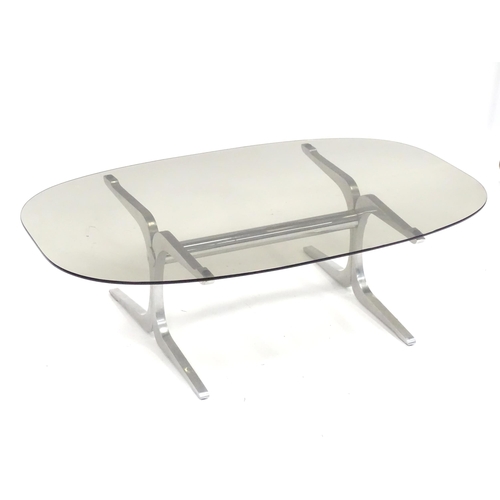 295 - A 20thC coffee table, with elliptical smoky glass top supported by a brushed aluminium frame. In the... 