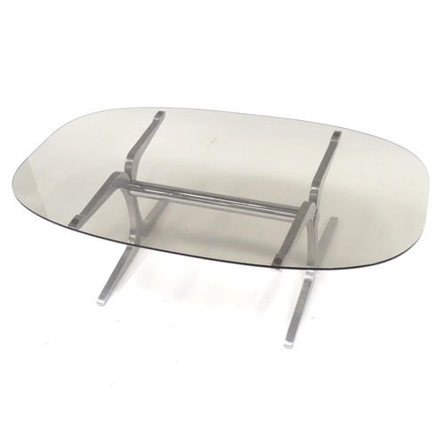 295 - A 20thC coffee table, with elliptical smoky glass top supported by a brushed aluminium frame. In the... 