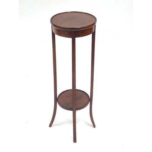 334 - An Edwardian mahogany jardiniere stand, with two circular tiers, decorated with boxwood stringing an... 